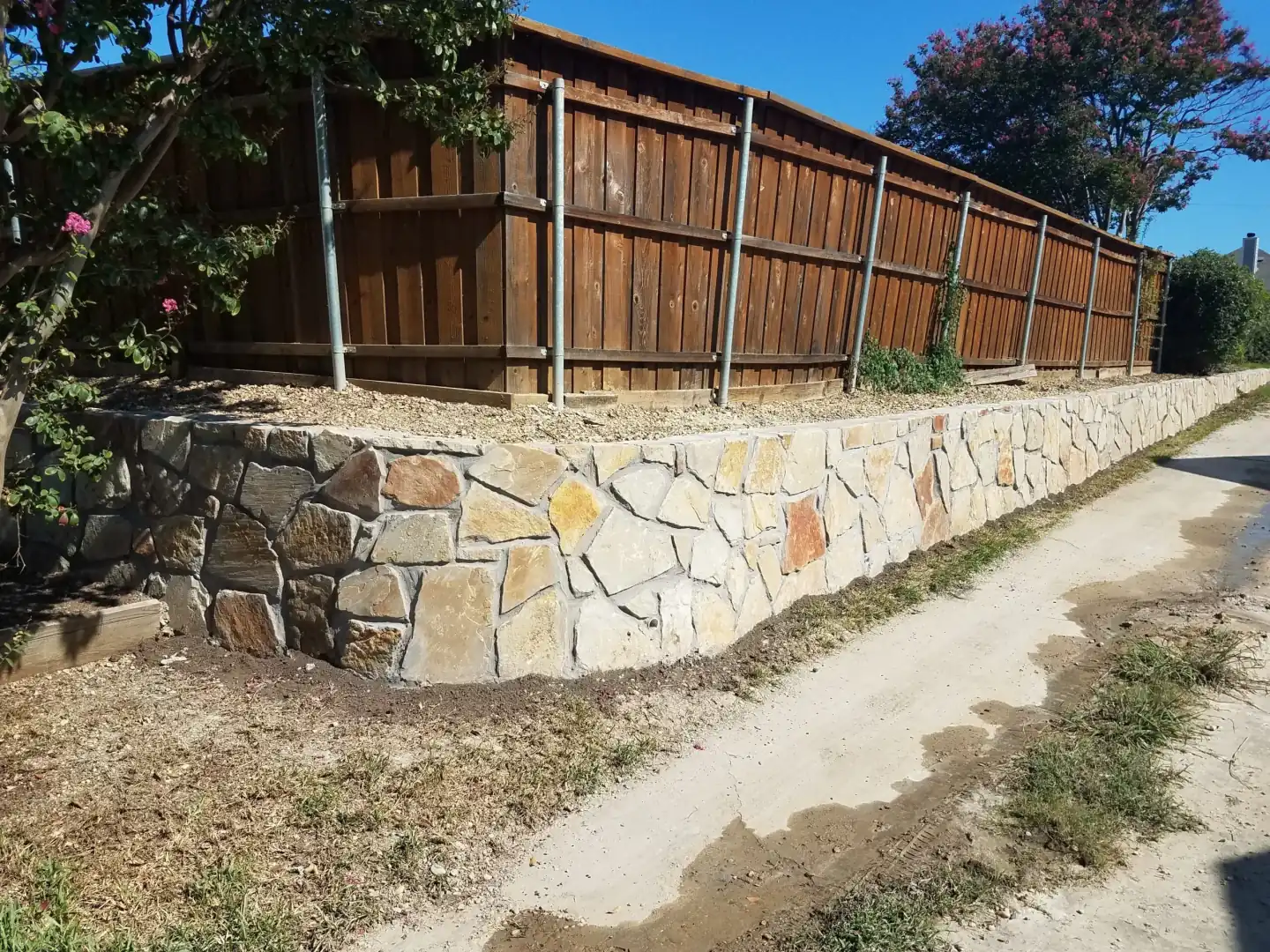 Granbury stone retaining wall following a fence line in Garland, TX Granbury stone retaining wall following a fence line in Garland, TX