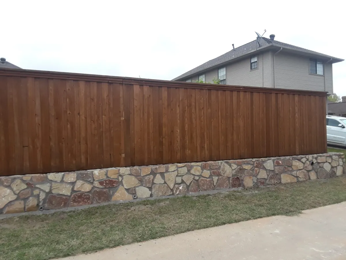 Granbury stone retaining wall beneath a wood fence in Colleyville, TX Granbury stone retaining wall beneath a wood fence in Colleyville, TX